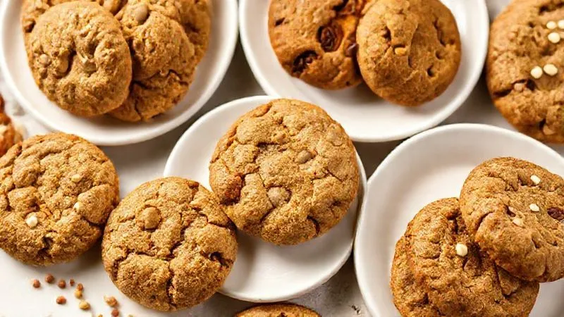 A beautifully styled, photorealistic spread of various perfectly baked, moist fit cookies: oatmeal-peanut butter cookies, carrot cake cookies, zucchini-chocolate cookies, and pumpkin spice cookies. Each cookie is visibly soft and slightly chewy, arranged on elegant white plates with a sprinkle of healthy garnishes like nuts and seeds. Cinematic lighting, sharp focus on the textures, depth of field, 8K, professional food photography, shot on a high-end DSLR.