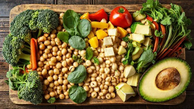 Photorealistic, professional photography, 8K, cinematic lighting, sharp focus, depth of field, shot on a high-end DSLR. A vibrant, colorful array of high-fiber vegetables and legumes neatly arranged in separate sections on a rustic wooden board, including broccoli florets, spinach leaves, chickpeas, kidney beans, sliced bell peppers, and avocado cubes, emphasizing freshness and nutritional richness.