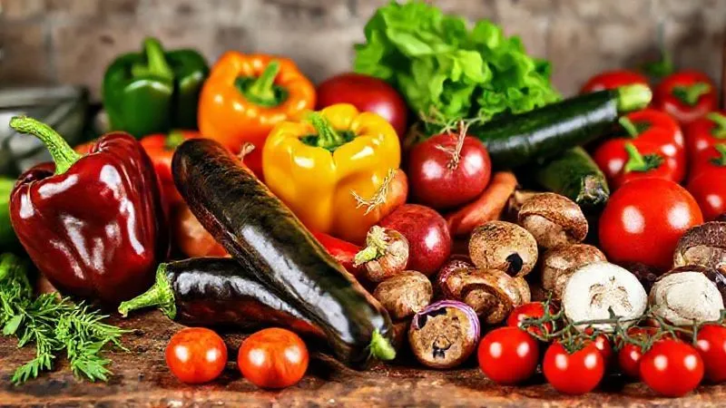 A vibrant assortment of fresh, raw vegetables suitable for grilling – bell peppers, zucchini, eggplant, red onions, mushrooms, and cherry tomatoes – neatly arranged on a rustic kitchen counter, ready for preparation. Photorealistic, professional photography, 8K, natural daylight, sharp focus, depth of field.