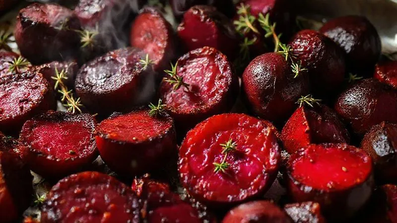 Photorealistic close-up of vibrant, freshly roasted beets on a baking sheet, lightly caramelized edges, garnished with fresh thyme, steam subtly rising, cinematic lighting, sharp focus, 8K hyper-detailed.