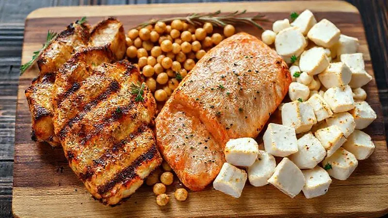 A photorealistic image of various lean protein sources arranged neatly on a wooden board: grilled chicken breast strips, baked salmon fillet, cooked chickpeas, and firm tofu cubes. Cinematic lighting, sharp focus, depth of field, 8K hyper-detailed, professional photography, shot on a high-end DSLR.