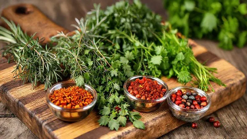 photorealistic, professional photography, 8K, cinematic lighting, sharp focus, depth of field shot of a rustic wooden cutting board laden with an array of vibrant fresh herbs like rosemary, thyme, and parsley, alongside small bowls of colorful spices such as smoked paprika, chili flakes, and whole peppercorns. The scene is beautifully composed, highlighting the natural textures and rich colors, suggesting culinary artistry and flavor enhancement.