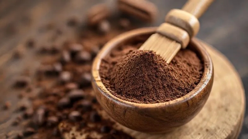 Photorealistic, professional photography, 8K, cinematic lighting, sharp focus, depth of field, shot on a high-end DSLR. A close-up shot of a small wooden bowl filled with rich, dark, high-quality cocoa powder, with a delicate dusting brush beside it, emphasizing the texture and depth of the ingredient.