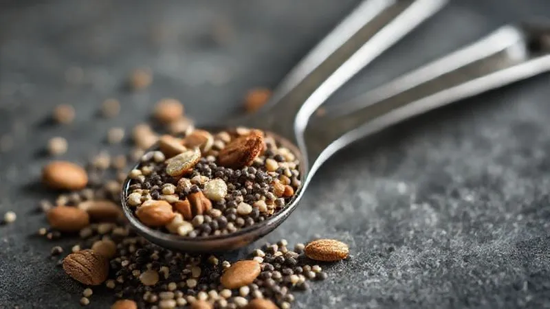 Photorealistic image of a measuring spoon next to a small, controlled portion of nuts and seeds (e.g., almonds, chia seeds), emphasizing precise portion control for smoothie ingredients, cinematic lighting, sharp focus on the measuring spoon, depth of field blurring the background, 8K hyper-detailed, shot on a high-end DSLR.