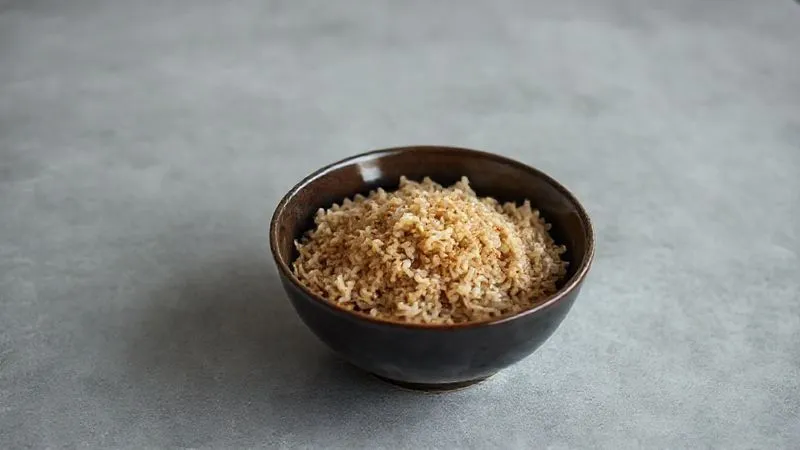 photorealistic, professional photography, 8K, cinematic lighting, sharp focus, depth of field, shot on a high-end DSLR, a single bowl of plain, unseasoned, slightly overcooked brown rice looking unappetizing on a minimalist grey table, evoking a sense of boredom and lack of inspiration in cooking